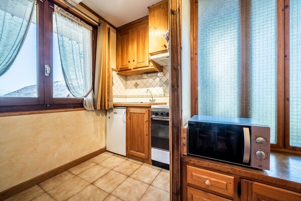 A kitchen with wooden cabinets, a microwave, a stove, and a sink.