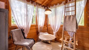 Interior de una cabaña de madera con una silla, una mesa y una escalera.