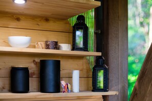 Une étagère en bois sur laquelle sont disposés divers objets, notamment un bol blanc, des récipients noirs, une lanterne et un petit jouet.