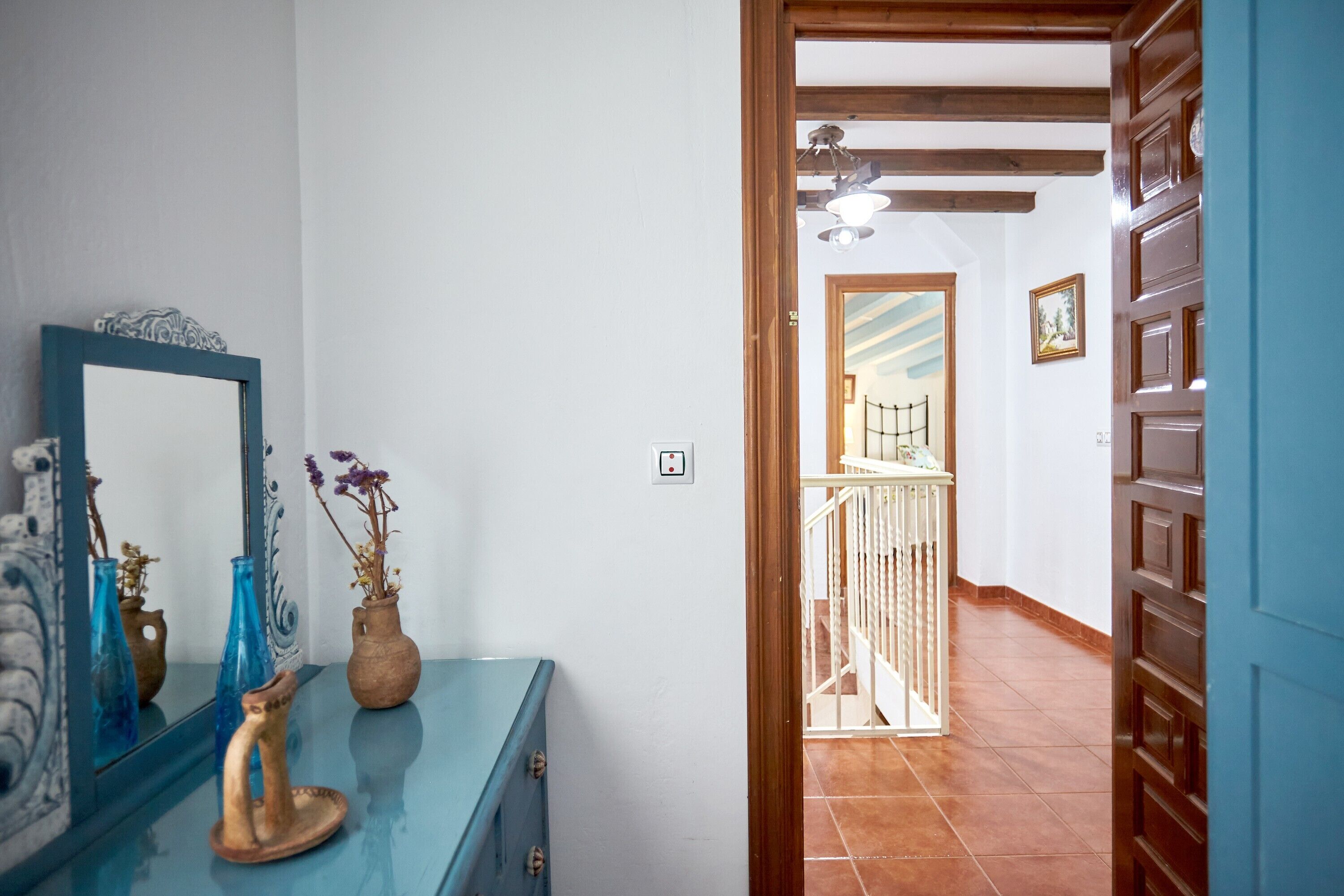 Un pasillo con un espejo, un aparador azul y una puerta de madera.