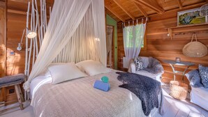 Een houten kamer met een bed, een bankje, een tafel en een hangmand.