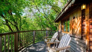 A wooden deck with Adirondack chairs, surrounded by trees. - Holiday treehouse "Bagheera" with Shared Pool, Private Terrace & Wi-Fi (Saint-Paul)