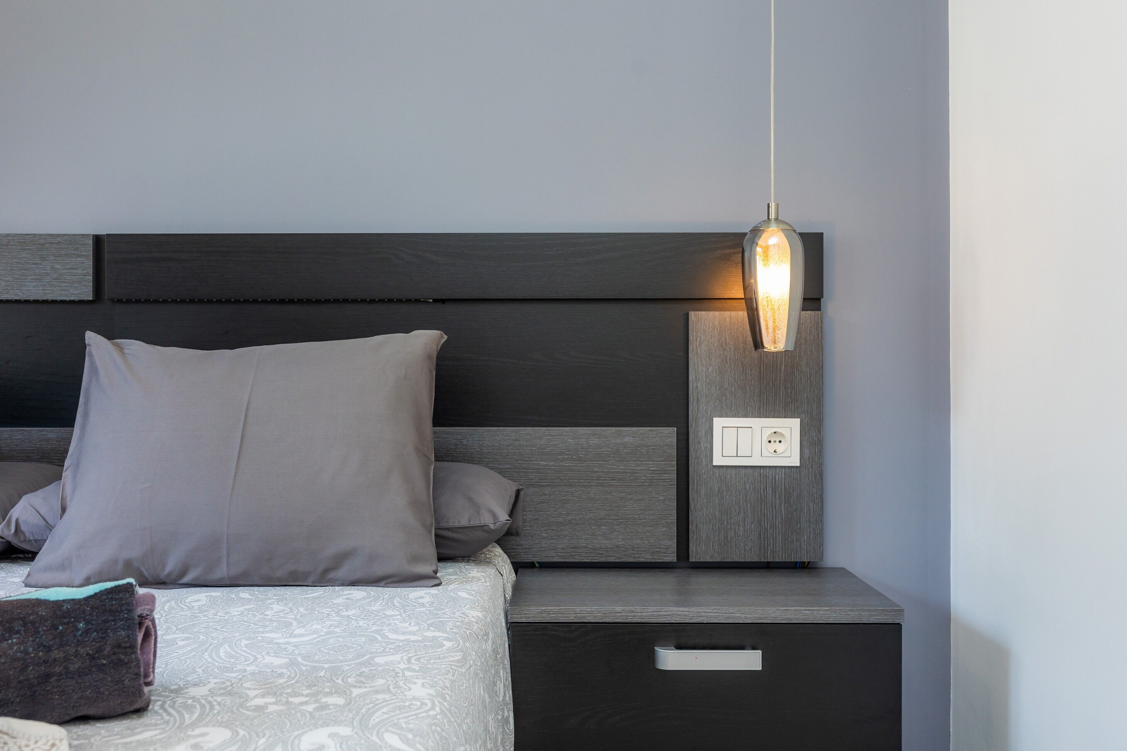 Une chambre à coucher moderne, avec un lit, des tables de chevet, une petite table et un luminaire fixé au mur.