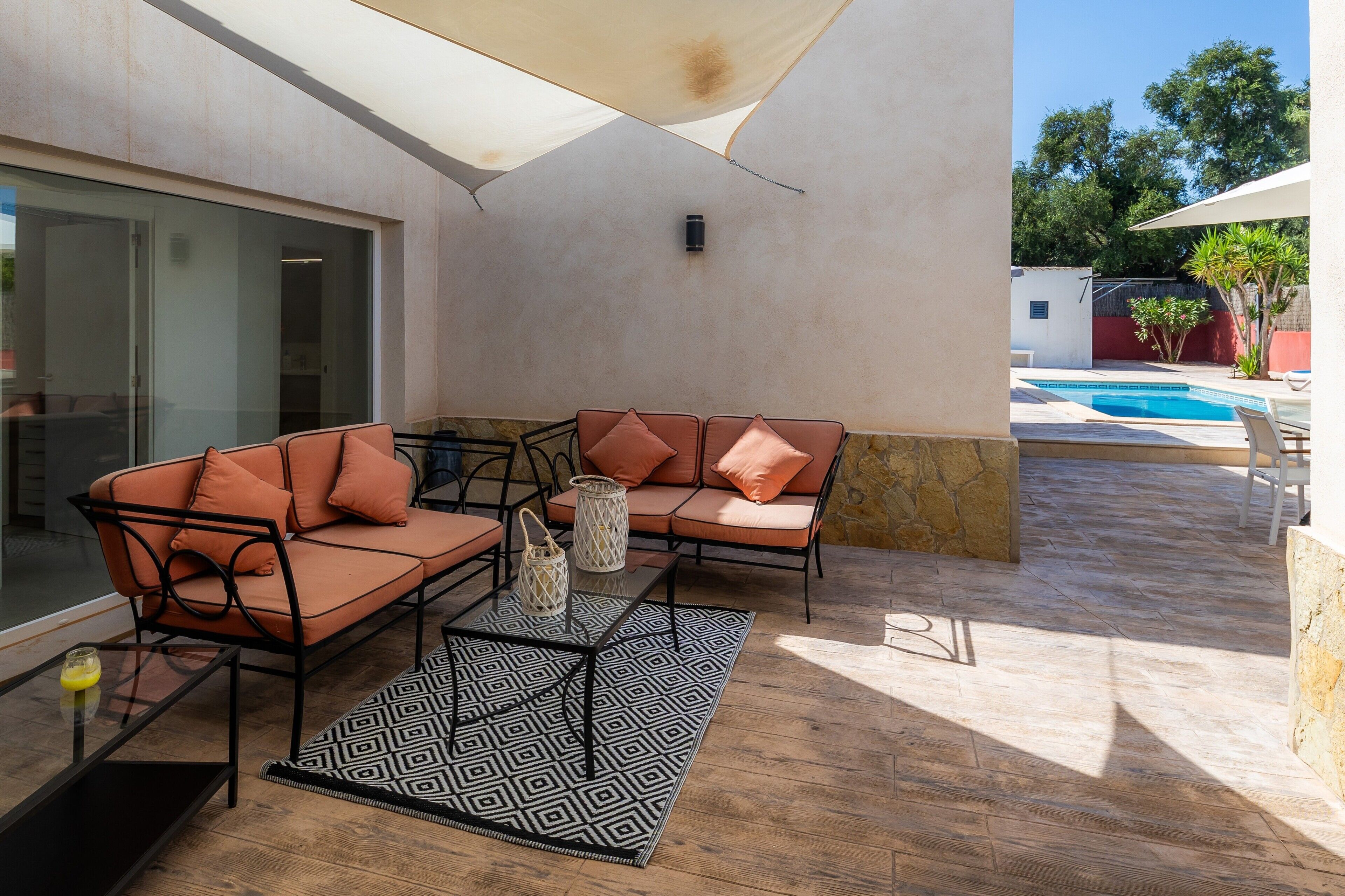 A patio with a sofa set, a coffee table, and a patterned rug.
