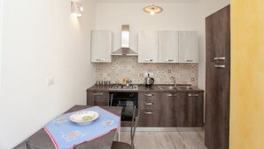 Une cuisine compacte comprenant un coin repas, un four encastré, une cuisinière et un évier.