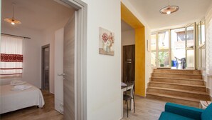 Une chambre à coucher comprenant un lit, un bureau et une chaise, un escalier, ainsi qu’un espace de vie avec un canapé.
