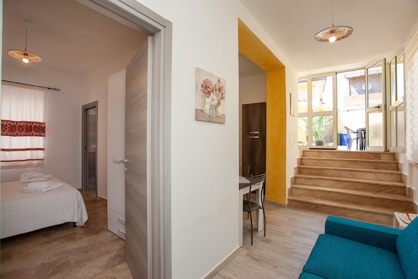 A bedroom with a bed, a desk, and a chair, a staircase, and a living area with a sofa.