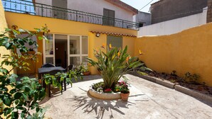 Une cour avec un jardinière ronde, du mobilier d’extérieur et des plantes en pot.