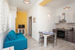 A compact living space with a kitchenette, a dining area, a sofa, and a television.