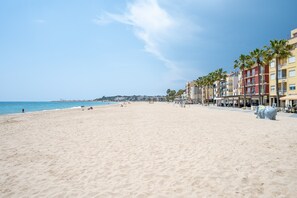 A beach with a row of colorful buildings, a clear sky, and a calm sea.