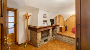 A room with a stone fireplace, wooden door, and a coat rack. - Apartment "Caratteristico e Accogliente" with Mountain View (Pila)