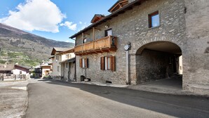 A stone building with a wooden balcony, a clear sky, and a mountain in the background. - Apartment "Caratteristico e Accogliente" with Mountain View (Pila)