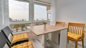A modern dining area with a wooden table and chairs, a potted plant, and a view of the sea through large windows. - Studio Apartment "Fetén Algarrobo Costa" with Sea View, Private Pool & Wi-Fi (Algarrobo Costa)