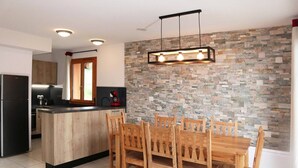 Une cuisine moderne avec un mur arrière en pierre, une table à manger en bois et des chaises.