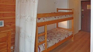 Una cama litera con ropa de cama estampada, un armario de madera y una puerta con un aviso.