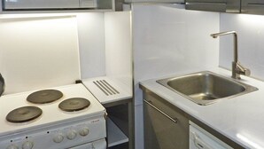 Una cocina compacta con estufa, microondas y pileta de acero inoxidable.