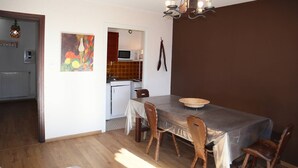 En matplats med ett bord för fyra personer, trästolar, en mikrovågsugn och en tavla på väggen.