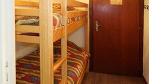 A room with bunk beds and a wooden door. - 2 Pièces 6 Personnes Centre Commercial (LES ORRES 1650)