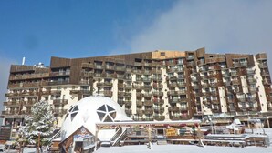 A multi-story hotel with balconies, a central dome structure, and outdoor seating areas. - Studio Équipé Pour 4 Personnes (LES ORRES 1650)