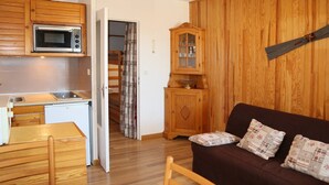 Un espacio habitable pequeño con kitchenette, muebles de madera y una zona de estar acogedora.