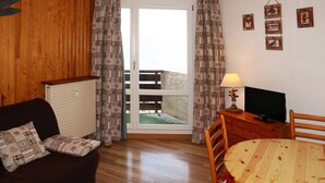 Una sala de estar acogedora con un sofá, una mesa de madera y un televisor.