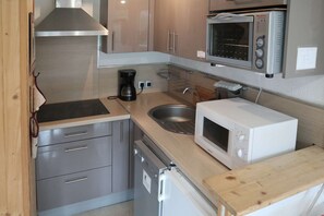Een koelkast, een oven, een vaatwasser, kookgerei, borden en bestek