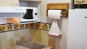 A compact kitchen with a microwave, a sink, a dishwasher, and a refrigerator. - Grand Appartement 6 Personnes (LES ORRES 1650)
