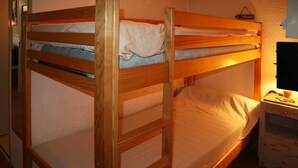 Una cama litera con estructura de madera y una mesita de noche con lámpara.