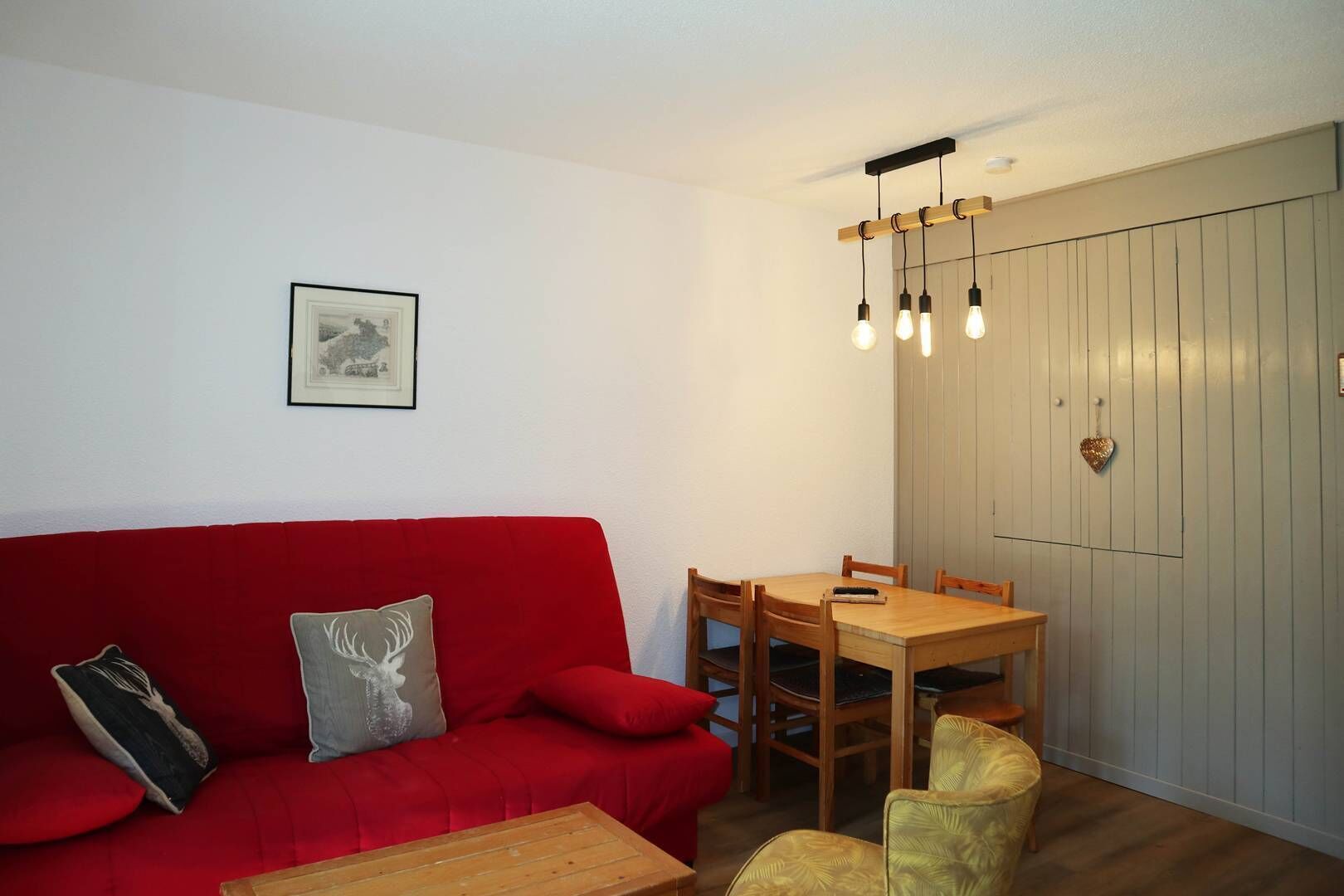 Un soggiorno accogliente con un divano rosso, un tavolo da pranzo in legno e un lampadario.