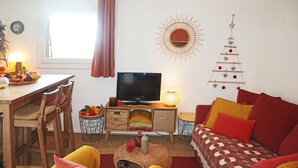 A cozy living room with a TV, wooden furniture, a fruit bowl, and a wall decoration. - 2 Pièces 6 Personnes en Cœur de Station (LES ORRES 1650)