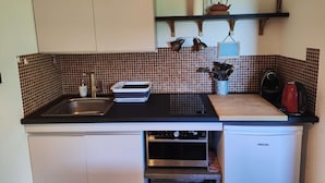 A compact kitchen with a sink, stove, and oven. There is a shelf above the counter holding kitchen utensils and a kettle. - 2 Pièces 6 Personnes en Cœur de Station (LES ORRES 1650)