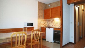 A compact kitchen with wooden cabinets, a microwave, a sink, and a small refrigerator. - 32 Orrianes des Forets (LES ORRES 1650)