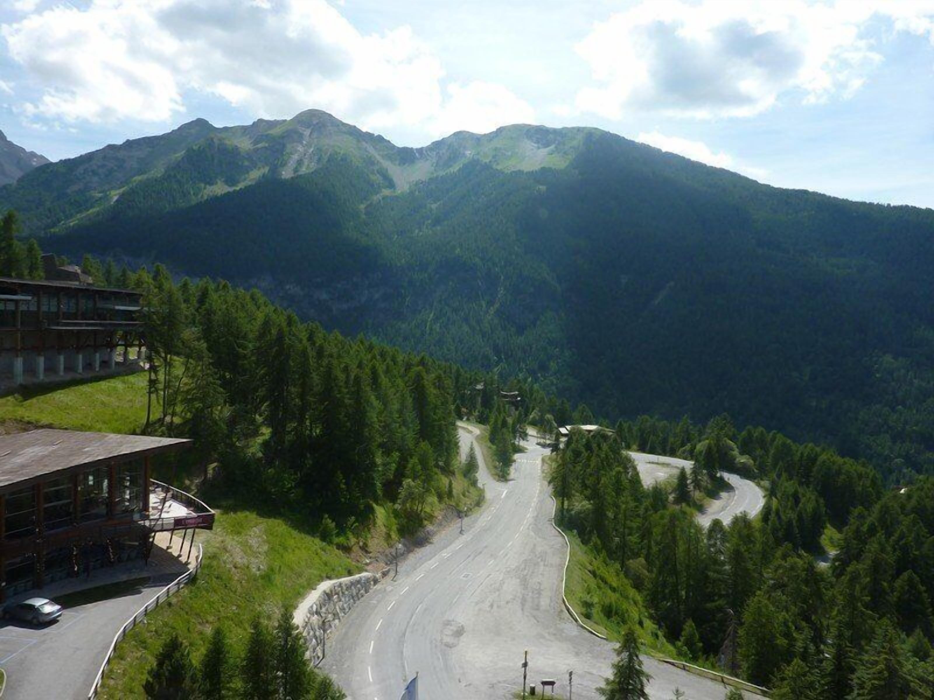 Une route de montagne avec un bâtiment sur la gauche.
