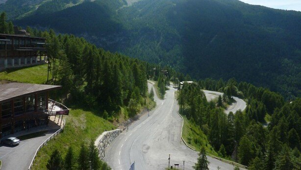 Une route de montagne avec un bâtiment sur la gauche.