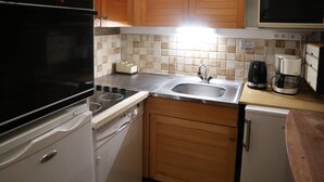 A compact kitchen with a stove, sink, and wooden cabinets. - 834 Orrianes des Forets (LES ORRES 1650)
