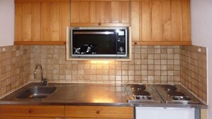 A kitchen with wooden cabinets, a stainless steel sink, a microwave, and a stove.