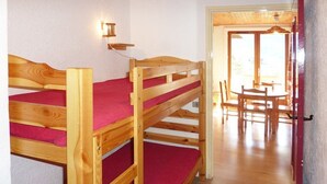 Un lit superposé avec un matelas rouge, une tête de lit en bois et un luminaire fixé au mur.