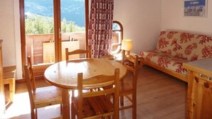 Un intérieur en bois avec une table ronde et des chaises, un canapé et une fenêtre donnant sur les montagnes.