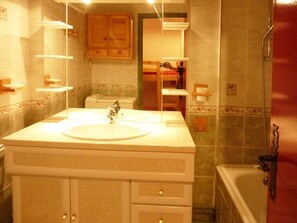 Casa de banho com lavatório, espelho e zona de duche.