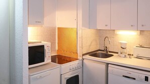 Cocina compacta con microondas, estufa, fregadero y cafetera.