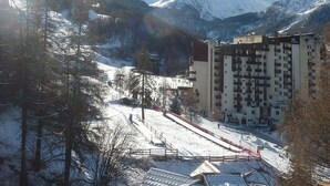 Un paisaje montañoso cubierto de nieve con un edificio de varios pisos en primer plano.