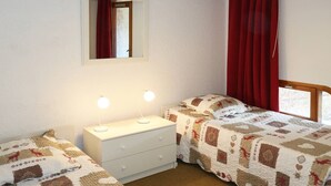 Un dormitorio con dos camas, un aparador, un espejo y cortinas rojas.