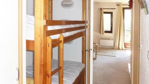 Een kamer met stapelbedden en een badkamer zichtbaar door een open deur.