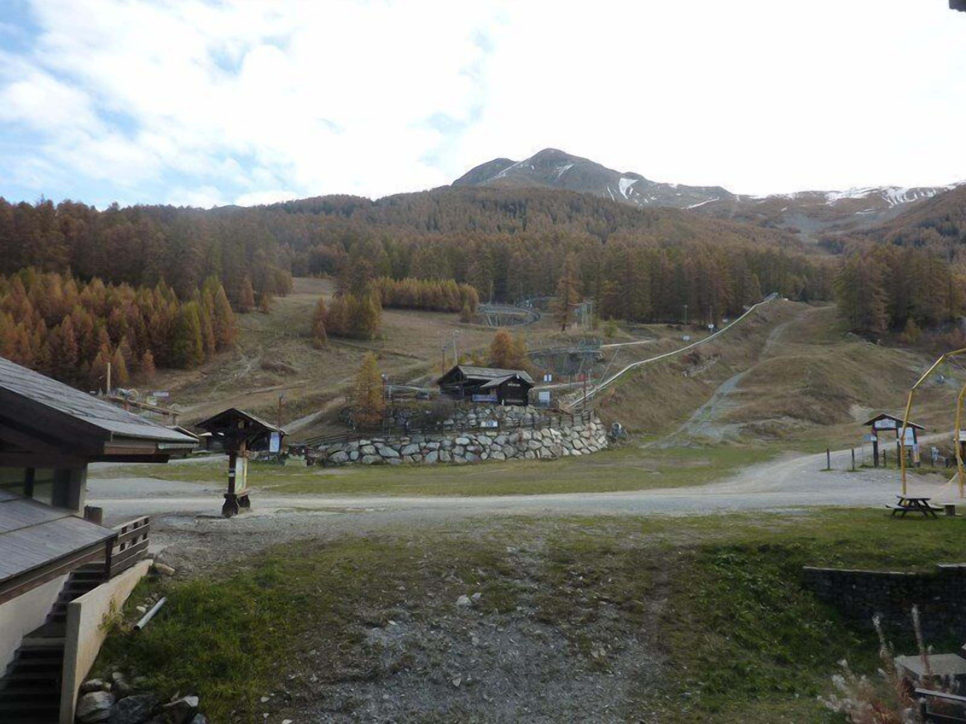 A mountain lodge with a stone foundation, wooden structures, and a clear view of the surrounding forest and mountains.