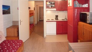 Une pièce de taille modeste comprenant un lit, un coin cuisine et un petit espace repas.