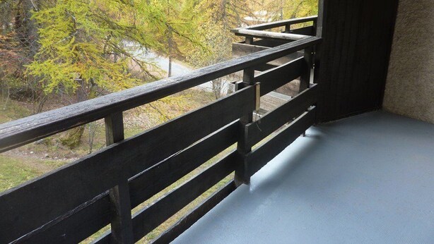 Un balcon donnant sur des arbres aux couleurs automnales.