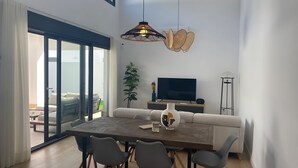 A modern living room with a dining table, chairs, a sofa, a TV, and a floor lamp. - Villa Tres Mares - Extraordinary accommodation. (Poblado de Sancti Petri)