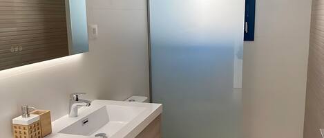 A modern bathroom with two sinks, a toilet, and a shower.