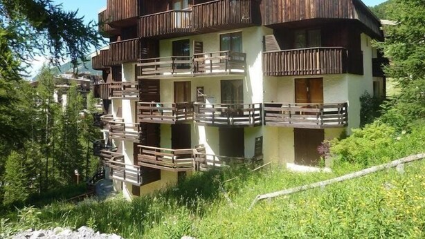 A multi-story wooden chalet with balconies, surrounded by greenery. - Studio 6 Personnes Accès Direct aux Pistes (LES ORRES 1650)