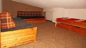 A small, compact room with two wooden bunk beds and a single bed, carpeted floor, and plain walls. - Studio 6 Personnes Accès Direct aux Pistes (LES ORRES 1650)